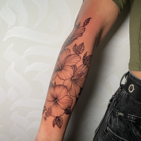 Delicado tatuaje de hibisco en el antebrazo