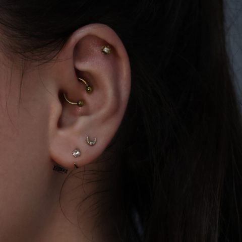 multiple ear piercings including a daith piercing, helix piercing and earlobe piercings