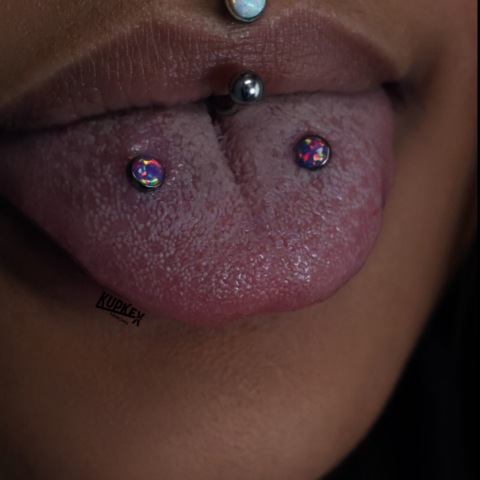 tongue piercings, snake bites and a philtrum piercing with white and black opals