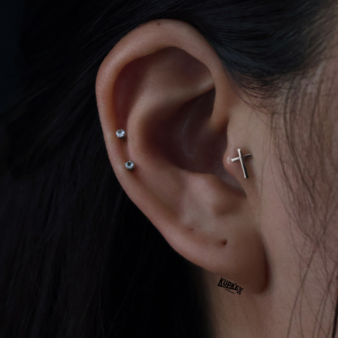 tragus piercing with a gold cross and 2 helix piercing with cubic zirconias